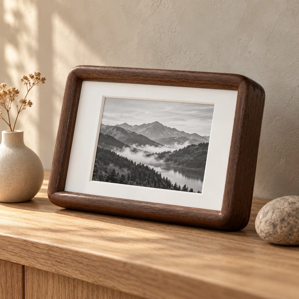 Walnut curved edge picture frame with a mountain photo on an oak shelf