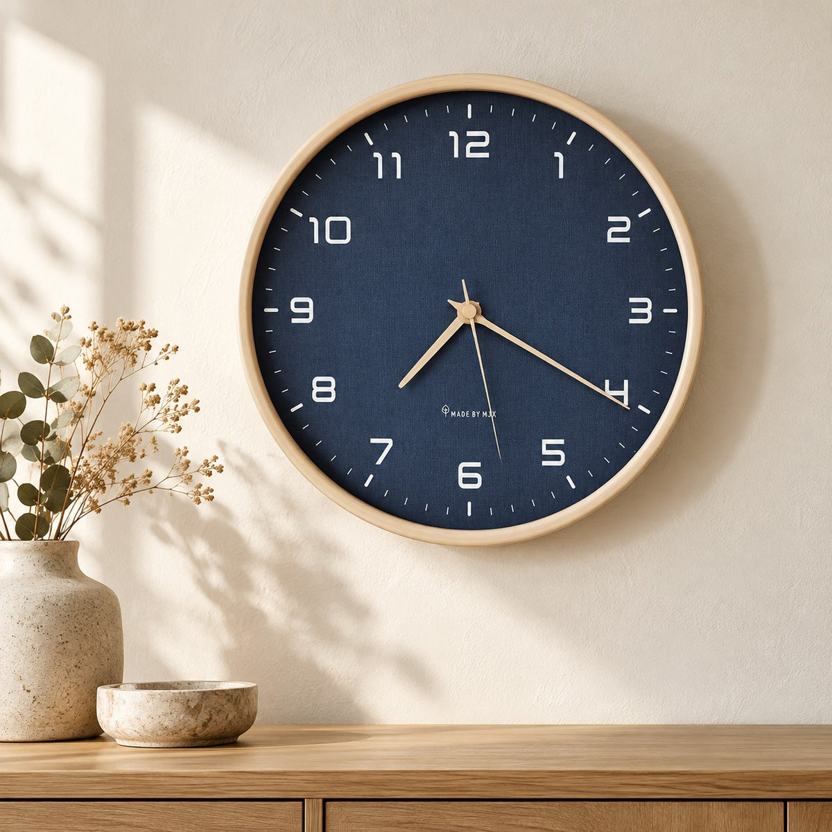Navy blue wall clock with a pale wood frame above an oak sideboard