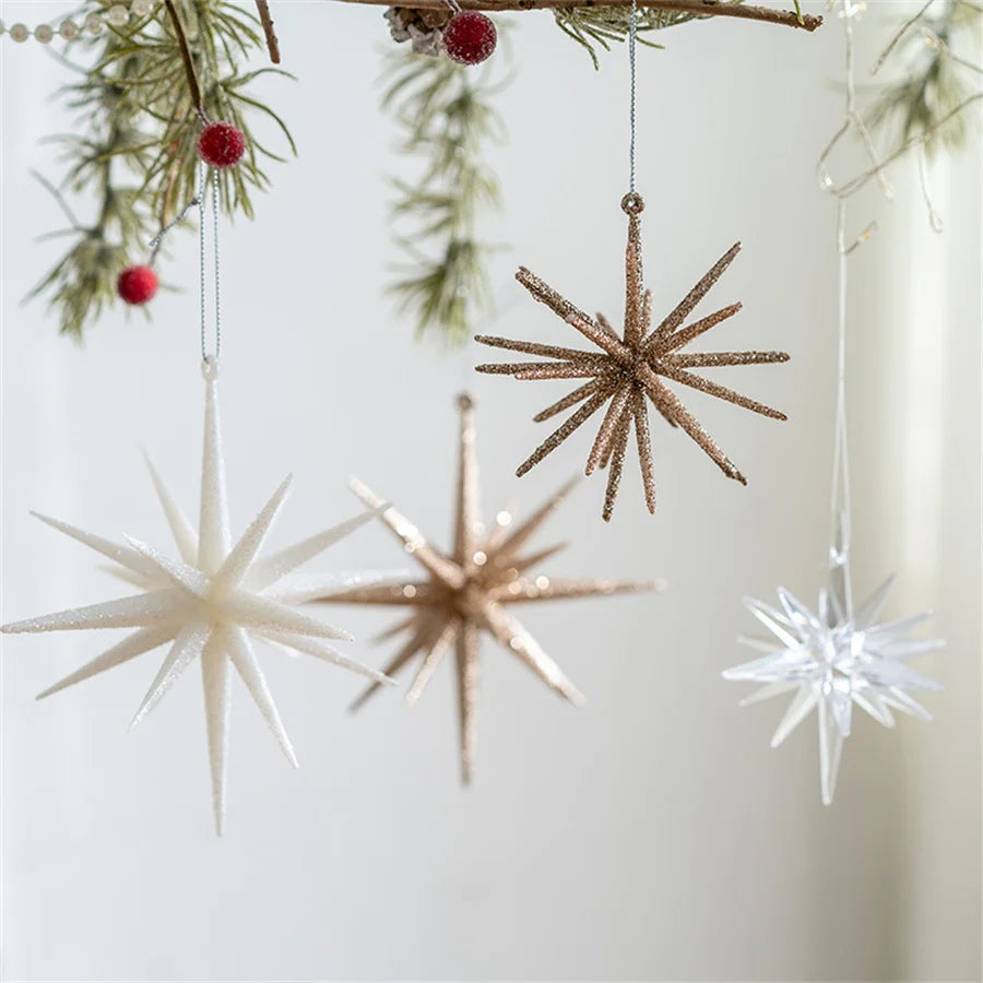 White, champagne and clear starburst ornaments hanging from a pine garland with red berries