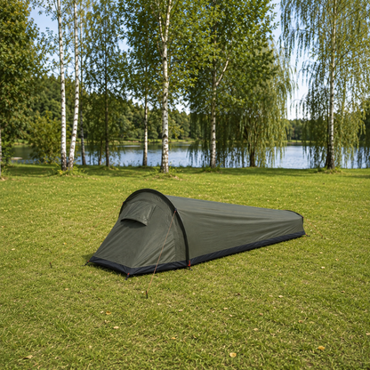 Army Green one-person backpacking tent pitched on grass beside a river on a bright morning