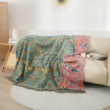 Botanical cotton bedspread draped over a cream sofa, green floral side and coral reverse side showing
