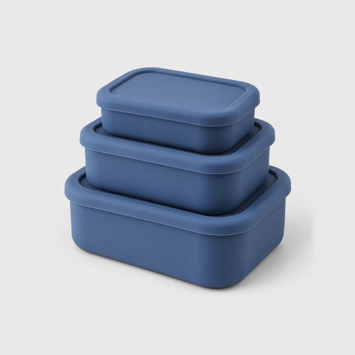 Three blue silicone food storage containers in small, medium and large, stacked with their lids on