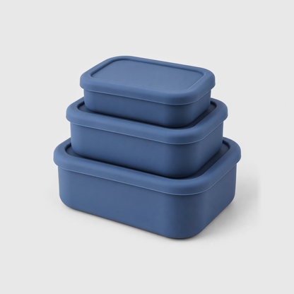 Three blue silicone food storage containers in small, medium and large, stacked with their lids on