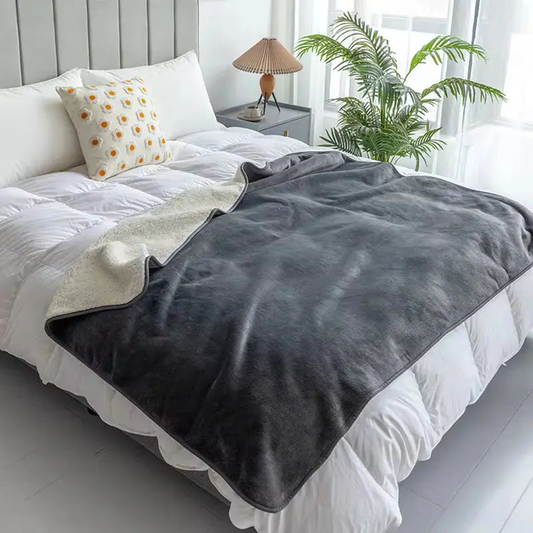 Gray waterproof pet blanket spread over a made bed, one corner turned back to show the cream fleece underneath