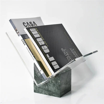 Green marble magazine holder with two magazines standing in its clear acrylic V, on a plain pale background