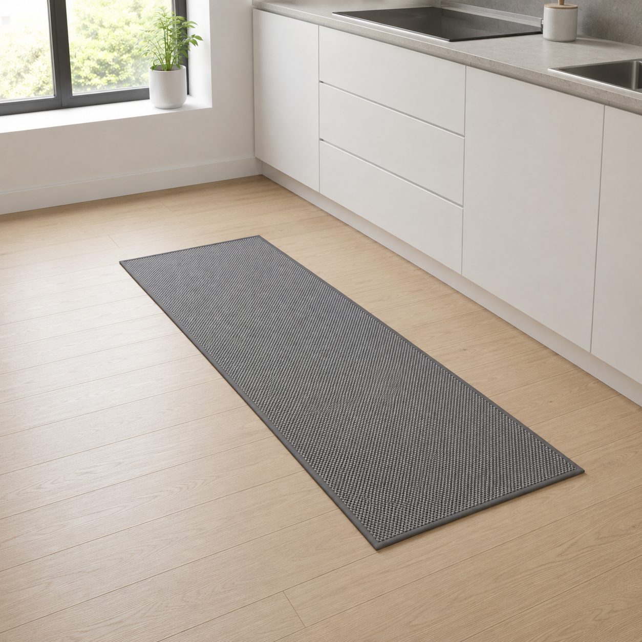Gray woven kitchen rug with non-slip rubber backing laid on a pale oak floor beside a white kitchen run