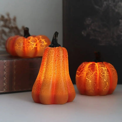 Three LED pumpkin lights lit on a table against a pale wall