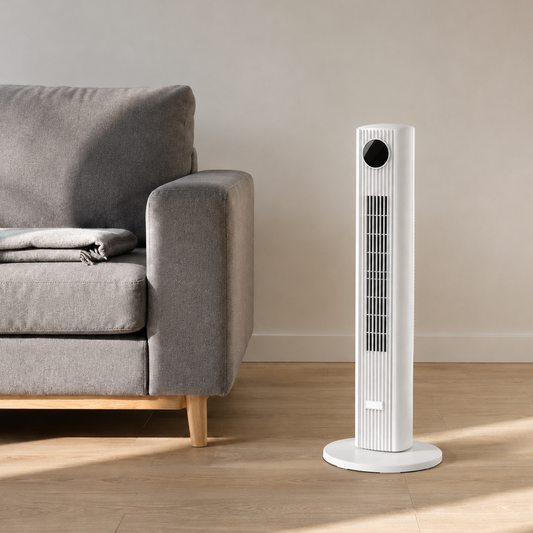 White tower fan standing beside a sofa in a bright living room