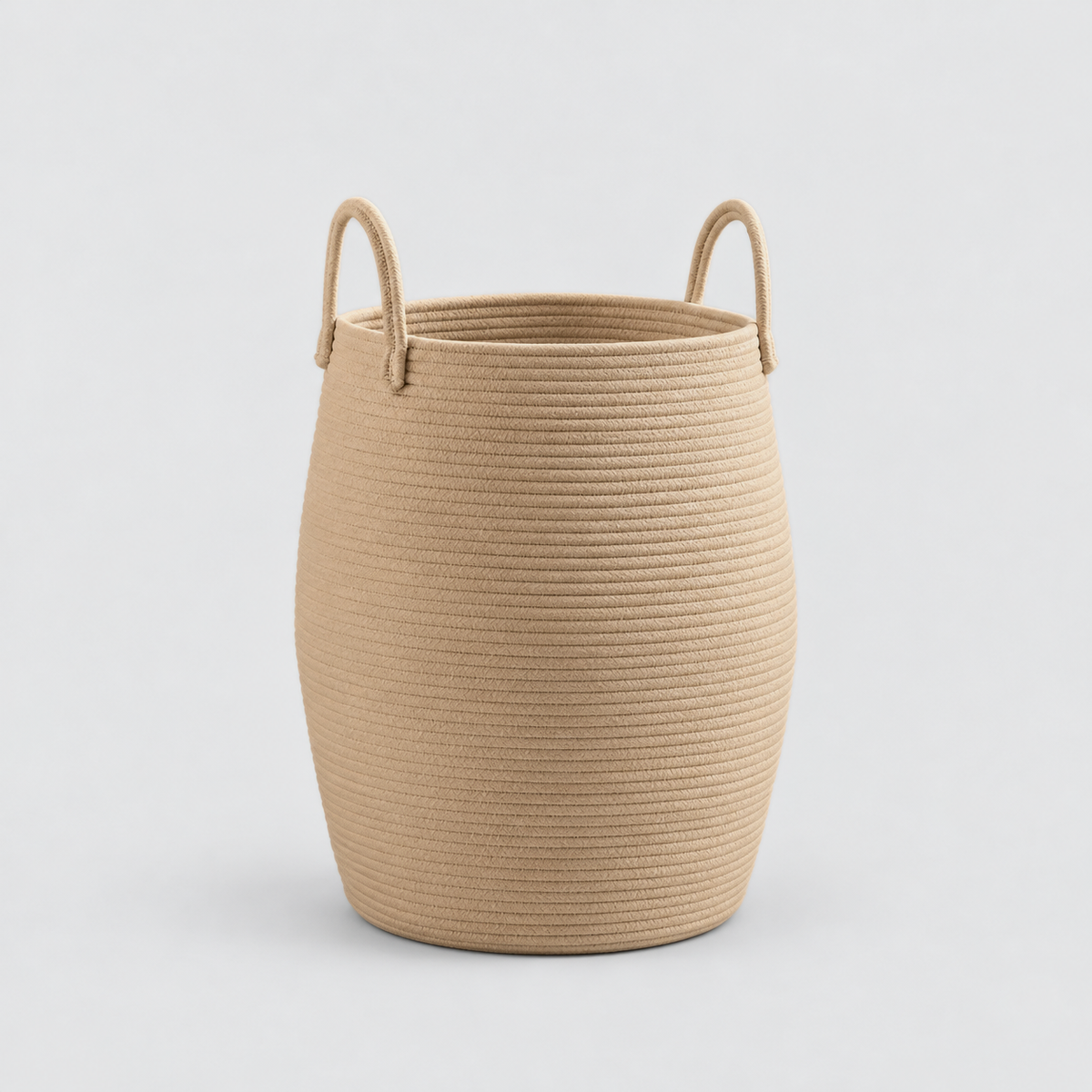 A tan rope laundry hamper with two rope handles, standing empty on a light grey background.