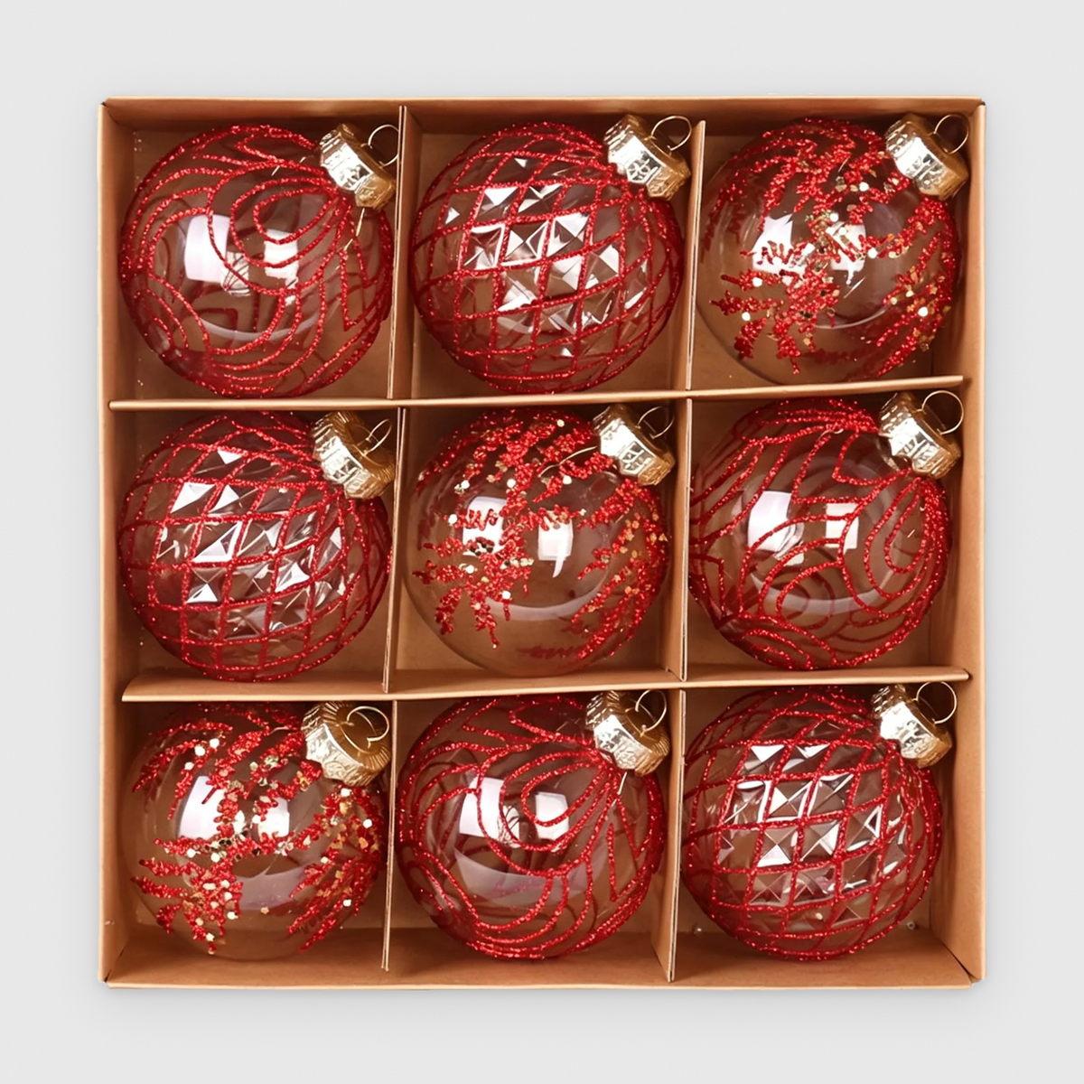 Box of 9 clear Christmas baubles with red glitter swirl, lattice and frond designs and gold caps