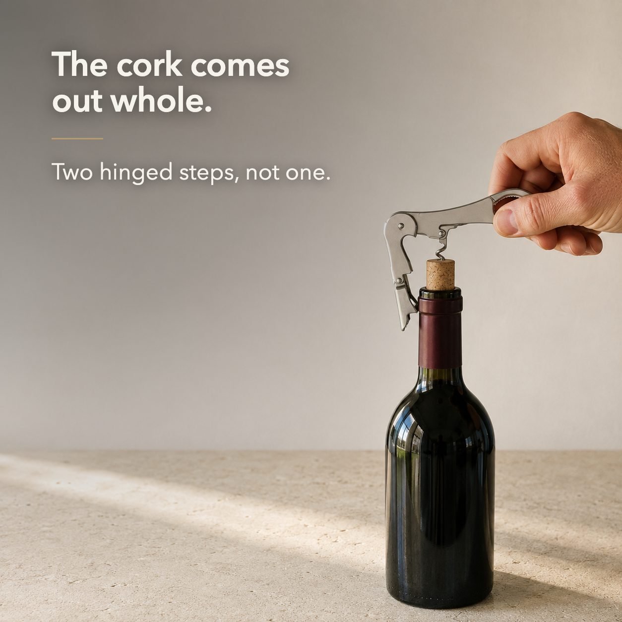 The cork comes out whole. Two hinged steps, not one, shown lifting a cork clear of a bottle of red wine