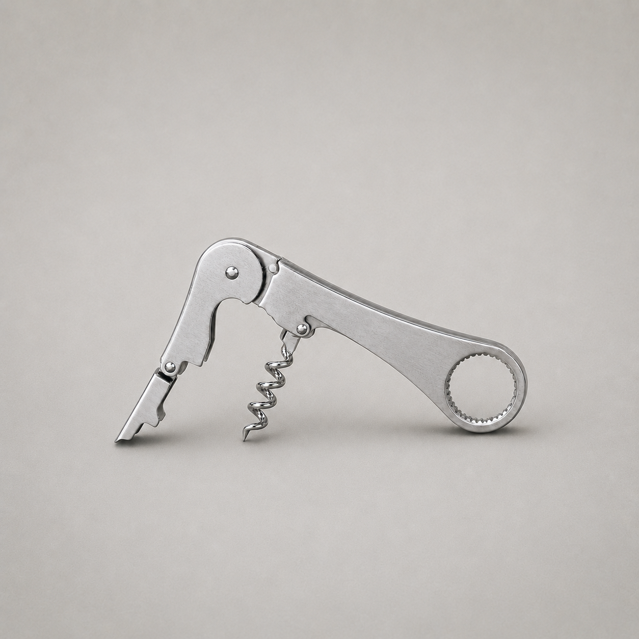 Stainless steel waiter's corkscrew open on plain grey, satin broad faces with mirror bright edges, rivets and worm, lever raised and open helix swung out
