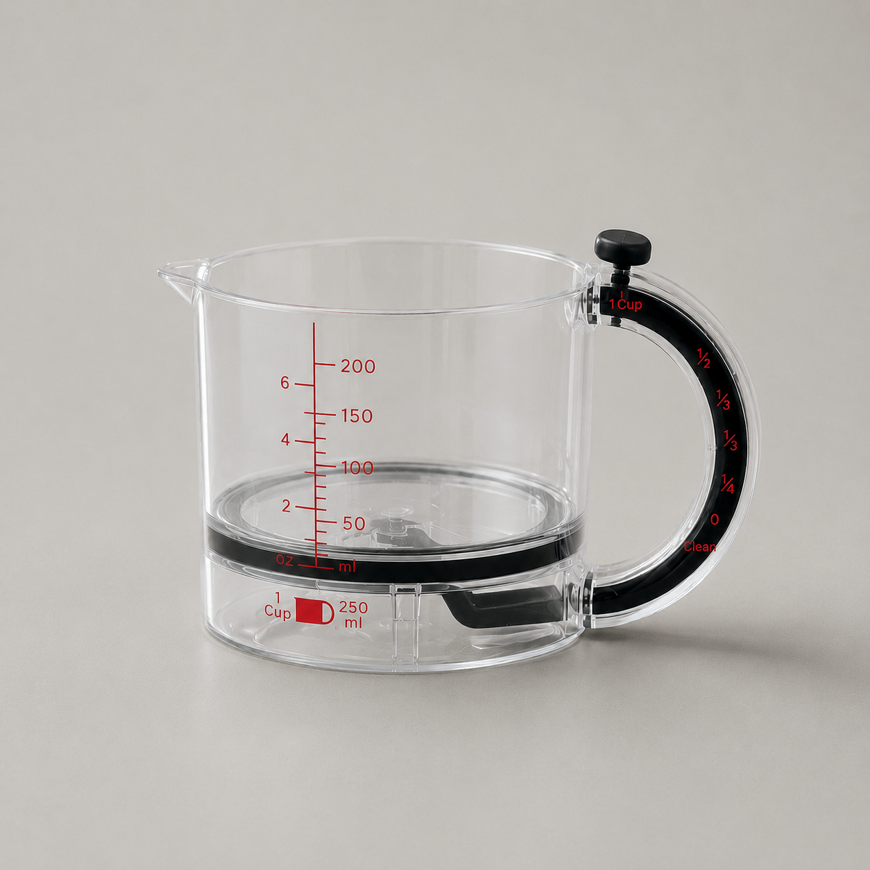 Clear adjustable measuring cup empty on plain grey, three-quarter view with the pour spout at the left, the loop handle and black dial knob at the right and the sealing plate lying flat inside