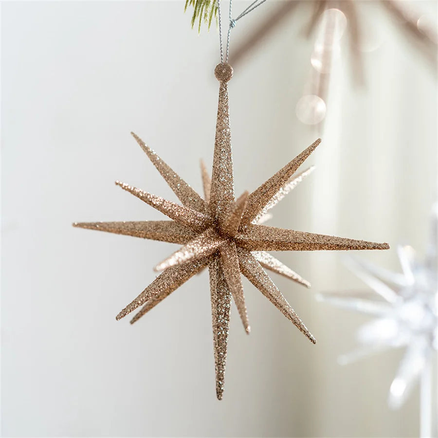 Large champagne glitter star ornament hanging from a pine branch in a bright room