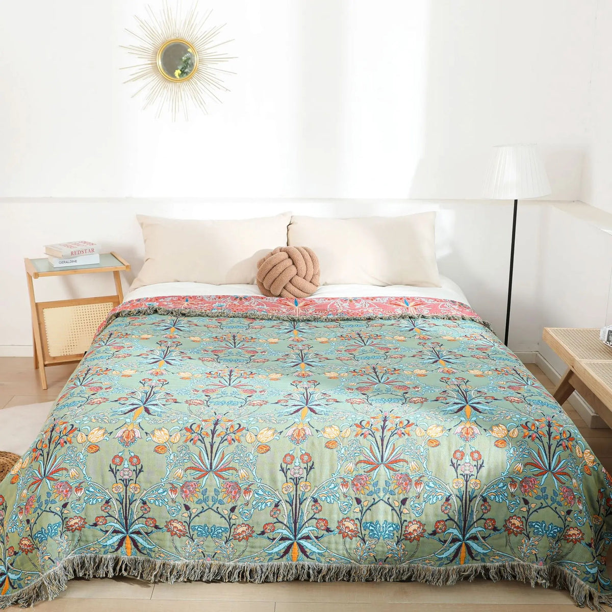 Green botanical cotton bedspread spread over a made bed with the fringe along the foot