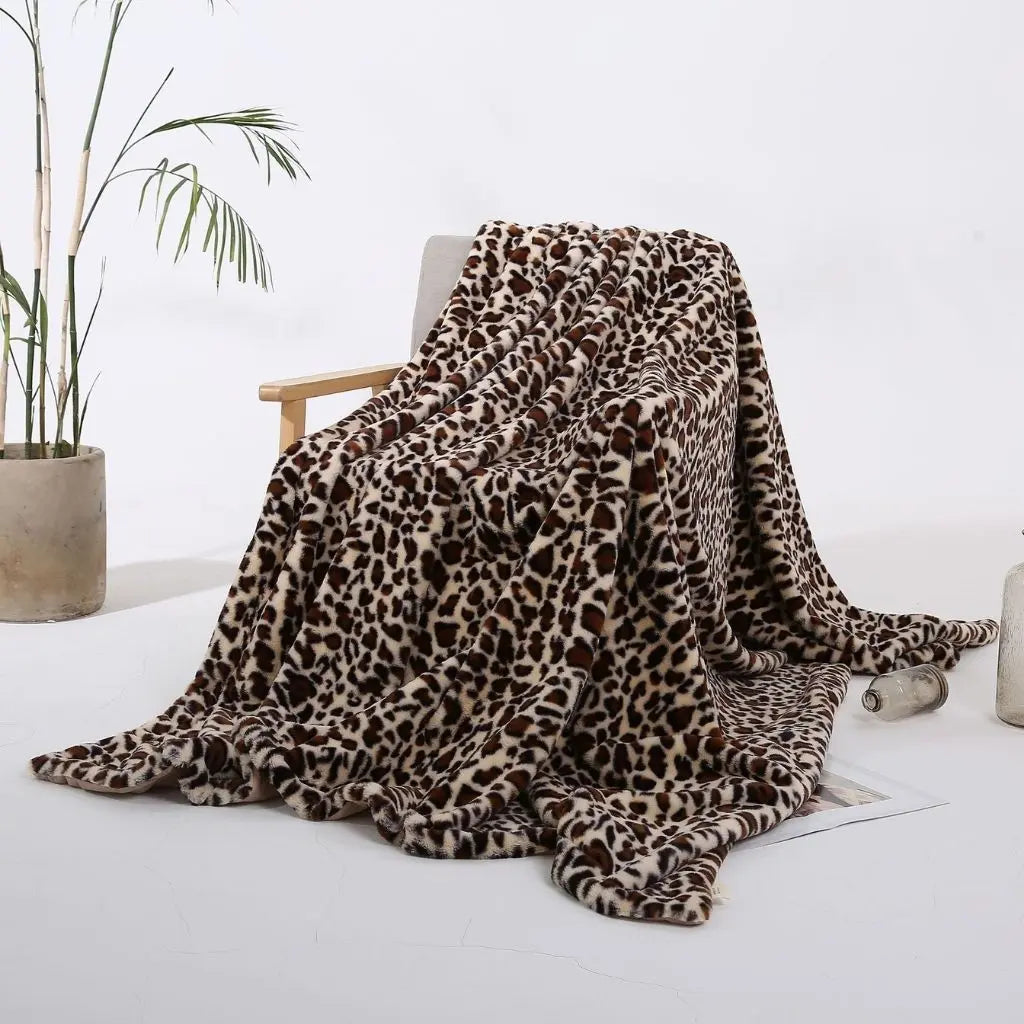 A beige leopard print throw blanket with dark brown spots, thrown over a wooden armchair and spilling onto a white floor.