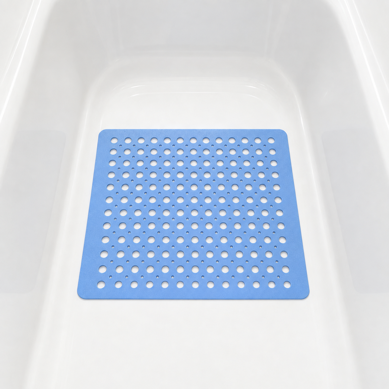 Blue non slip shower mat with drainage holes lying in the base of a white bathtub