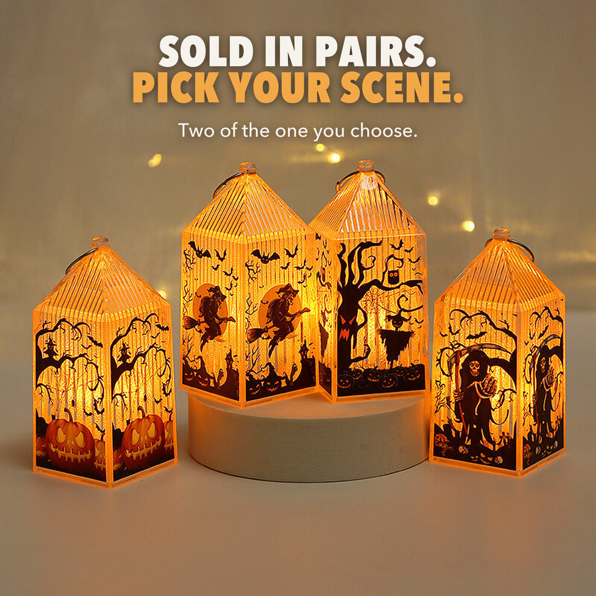 Four mini Halloween lanterns lit on and beside a round plinth, with the words Sold in pairs, pick your scene