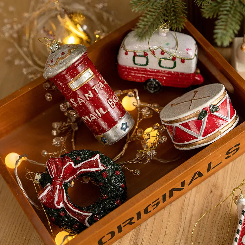 Mailbox, camper trailer, drum and wreath Christmas ornaments in a wooden tray with warm fairy lights and pine branches