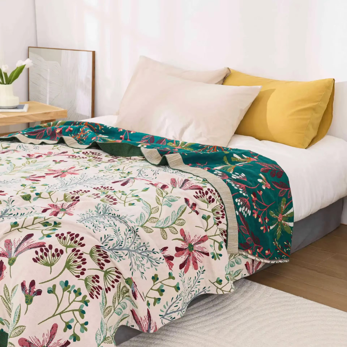 Cream wildflower blanket across a bed, turned back at the head to show the teal floral reverse and the oatmeal band