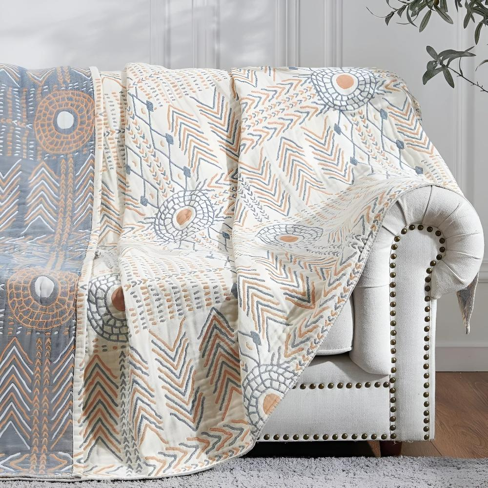 Cotton muslin throw draped over a cream sofa arm, the cream sun and chevron face beside a slate blue reverse panel