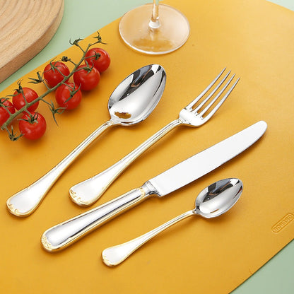 Mirror-polished flatware with gold-trimmed scroll handles laid on a yellow table mat