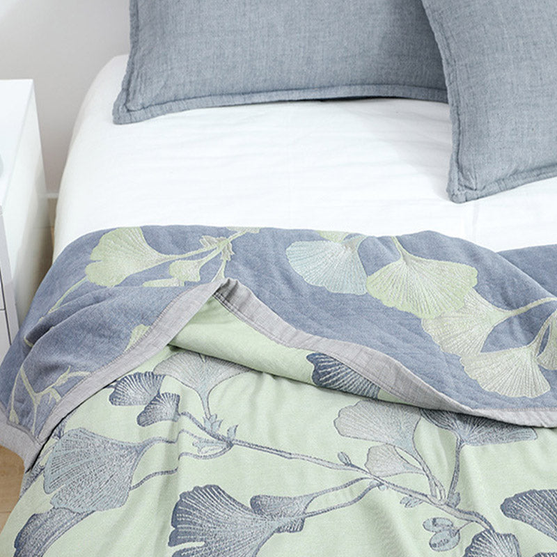 Green ginkgo leaf quilt on a bed with the top corner turned back to show the slate gray reverse and pale green leaves