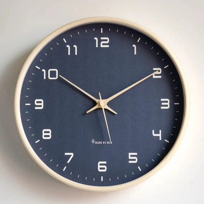Round wall clock with a navy blue face, white Arabic numbers, pale gold-tone hands and a natural wood frame