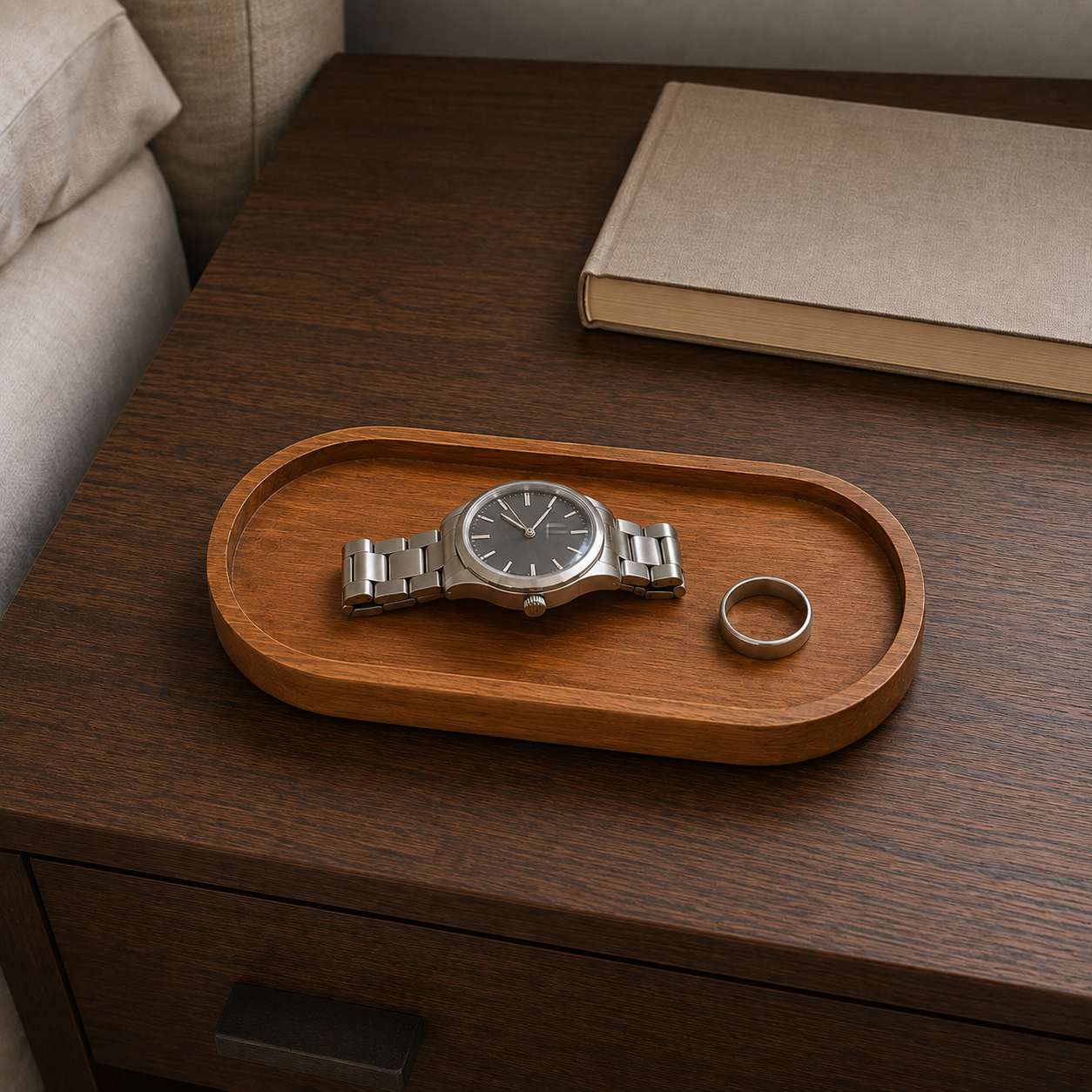 Small oval wooden tray on a nightstand holding a watch and a ring