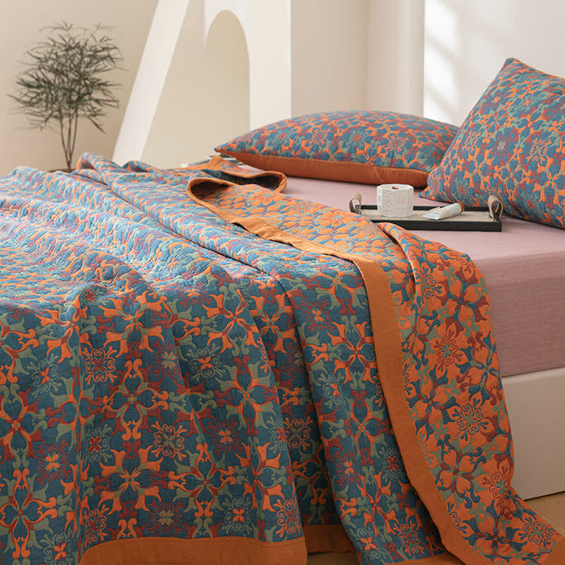 Six layer cotton quilt spread down a bed, its blue patterned face on top and the orange reverse folded along the side