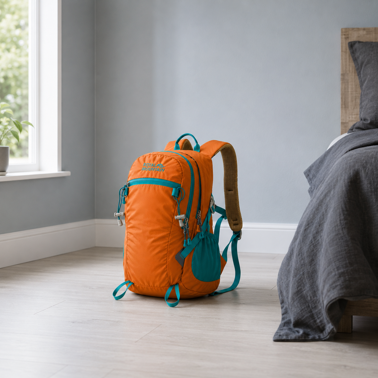 Orange 30L hiking day pack with teal trim standing on a bedroom floor in daylight