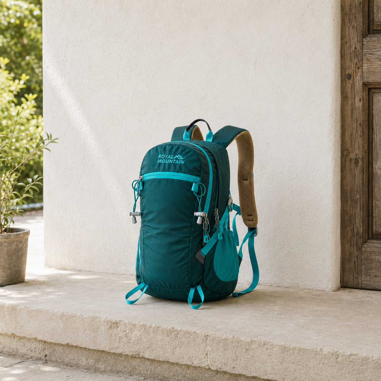 Dark green 30L hiking day pack with teal trim standing on a stone porch step in daylight