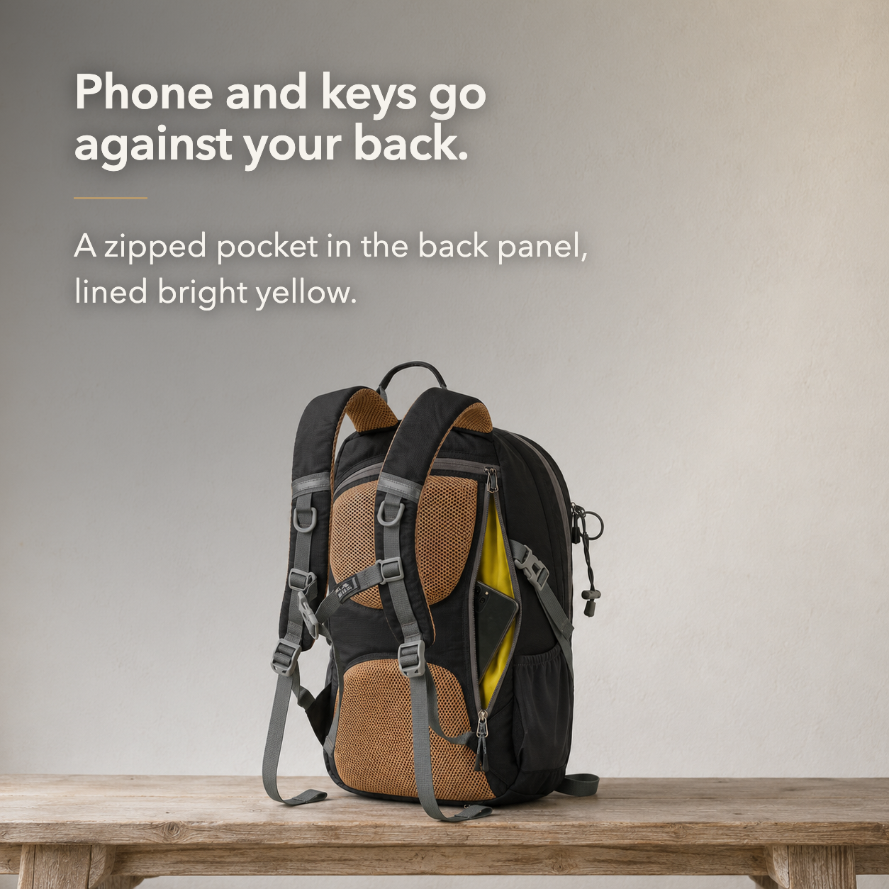 The hiking day pack seen from behind with the back panel pocket unzipped, its bright yellow lining showing and a phone slid inside