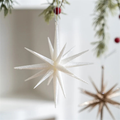 Large white glitter star ornament hanging in daylight with a champagne star behind it