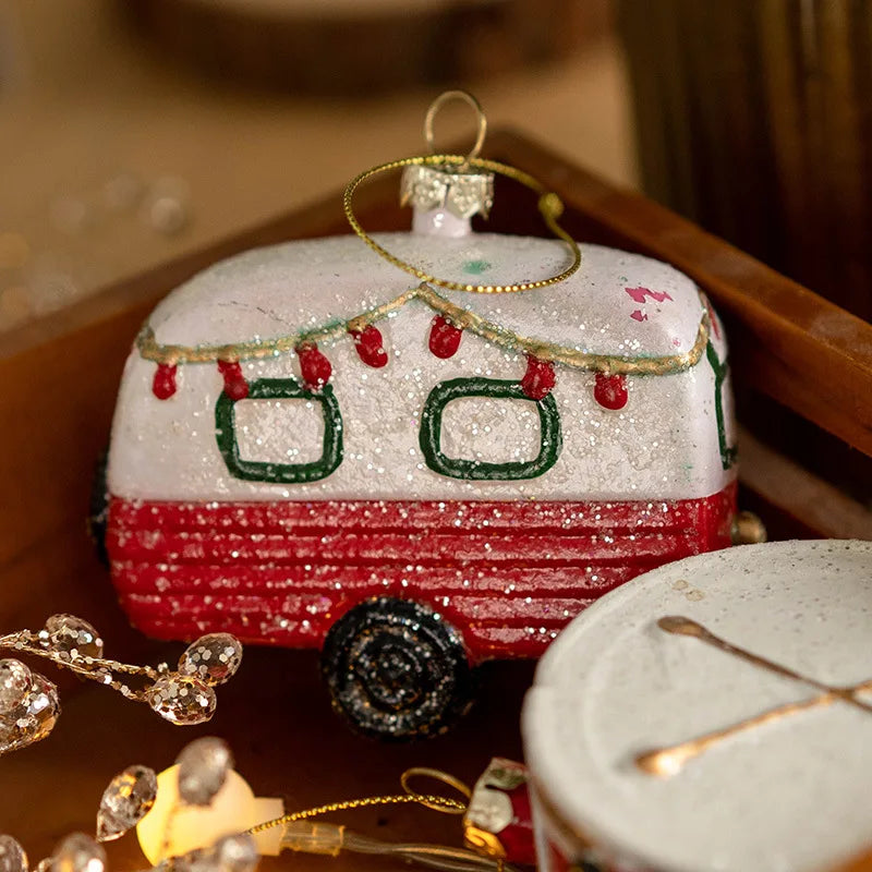 Close-up of the glittered camper trailer ornament with red string lights, green windows and a ribbed red lower half