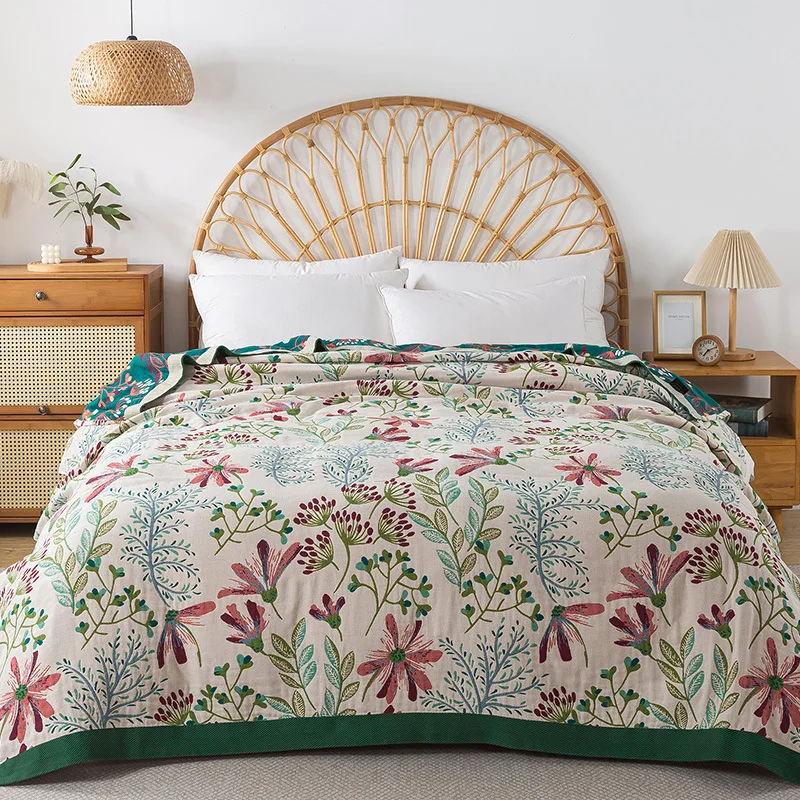 Cream wildflower blanket covering a bed with a rattan headboard, its dark green band hanging along the foot