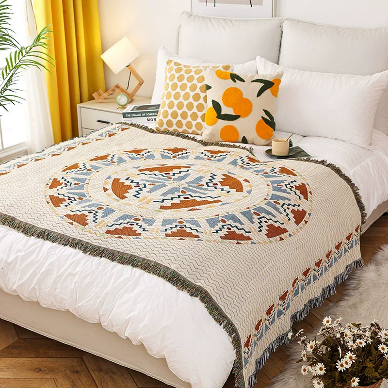 A cream jacquard throw with one large terracotta and powder blue sunburst, spread across the foot of a made white bed