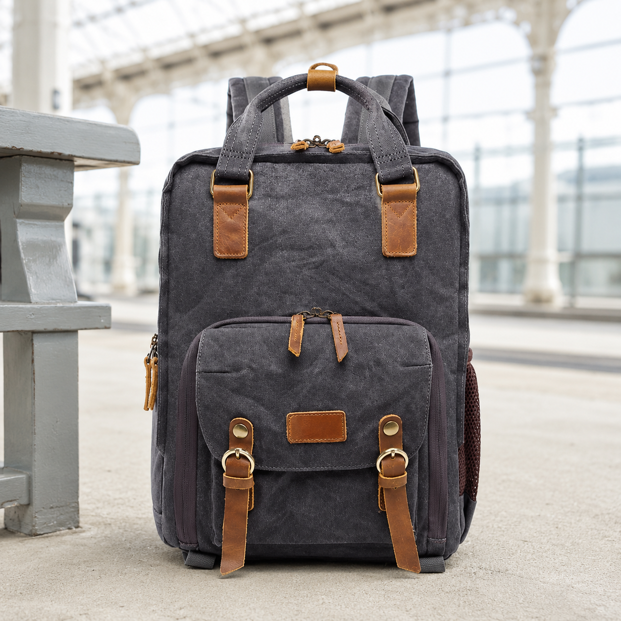 Charcoal gray waxed canvas camera backpack on a bright station platform.