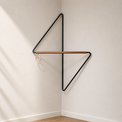 Black metal corner coat rack sitting empty in a hallway corner, showing the open pinwheel frame with one arm above the crossbar and one below.