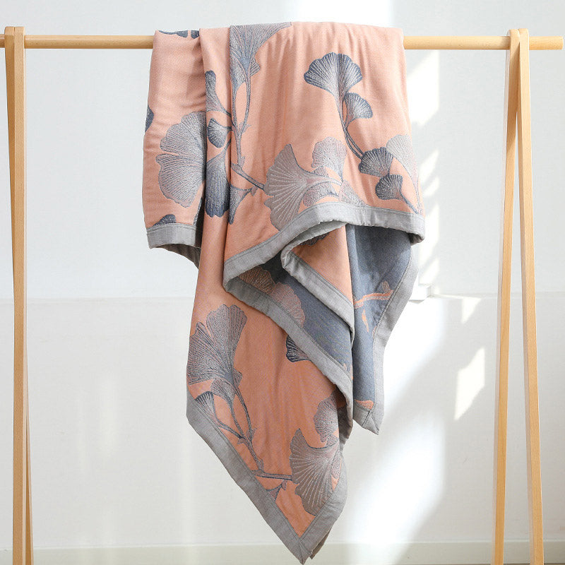 Peach ginkgo leaf quilt hung over a wooden clothes rail, showing the slate gray reverse and the gray border