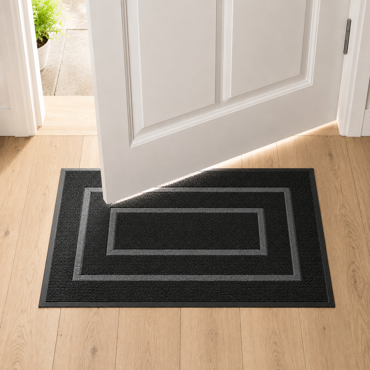 Black door mat on oak floorboards with a white door swinging open above it, showing the gap between the door and the mat.