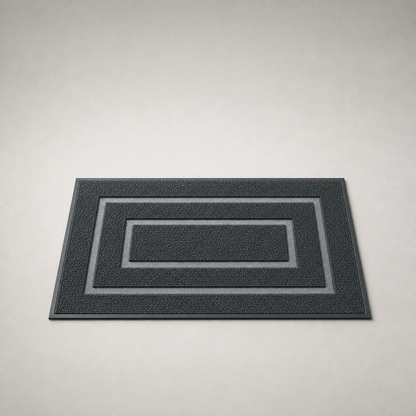 Black door mat on a plain gray studio background, seen from a low three-quarter angle.
