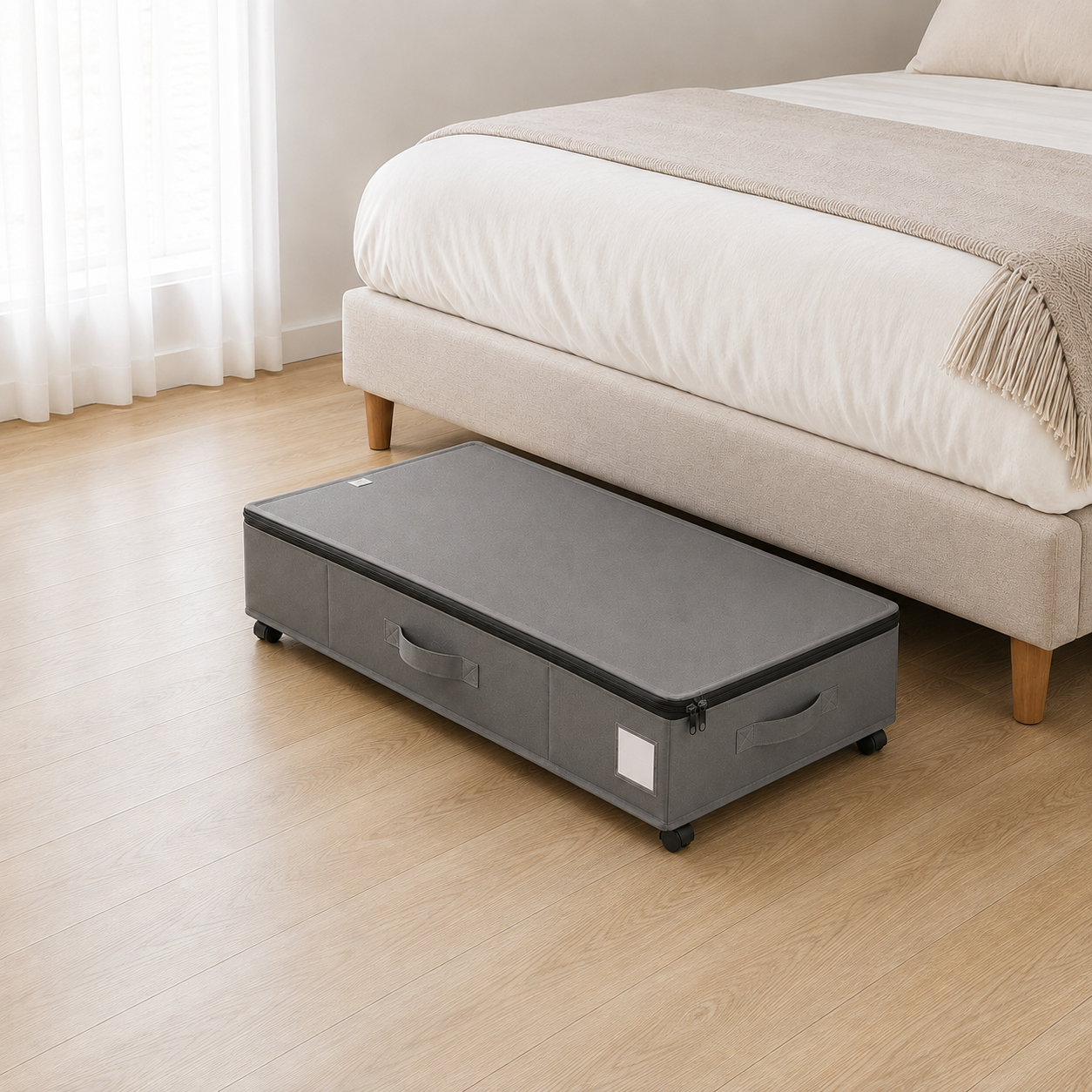 Gray under bed storage box on castors, lid zipped shut, standing on pale oak floorboards beside a bed.