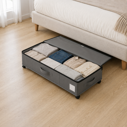 Gray under bed storage box open with the lid folded back along its long edge, folded sweaters and jeans packed inside.