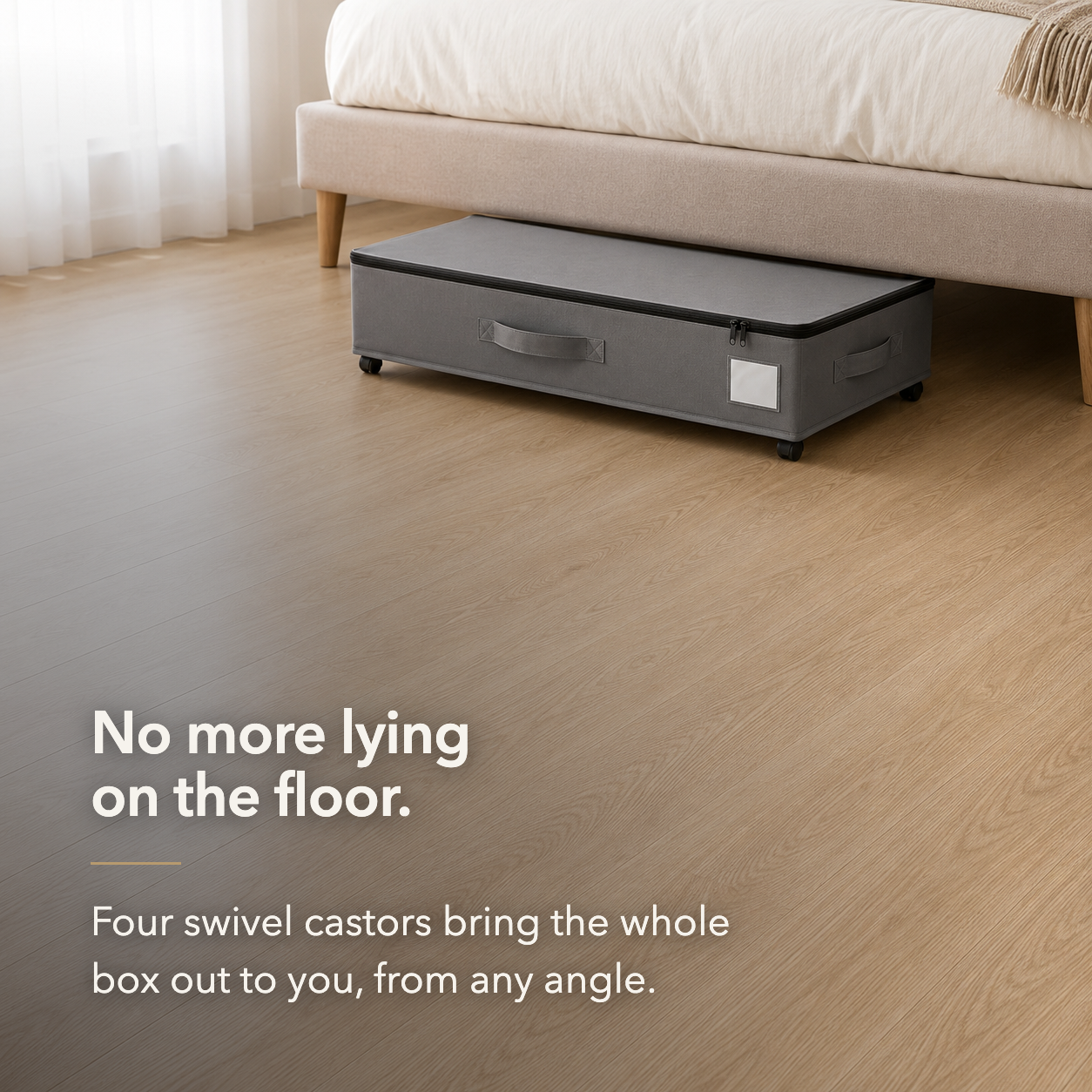 Gray under bed storage box rolled out from under a bed on its four swivel castors, with clear floor around it.