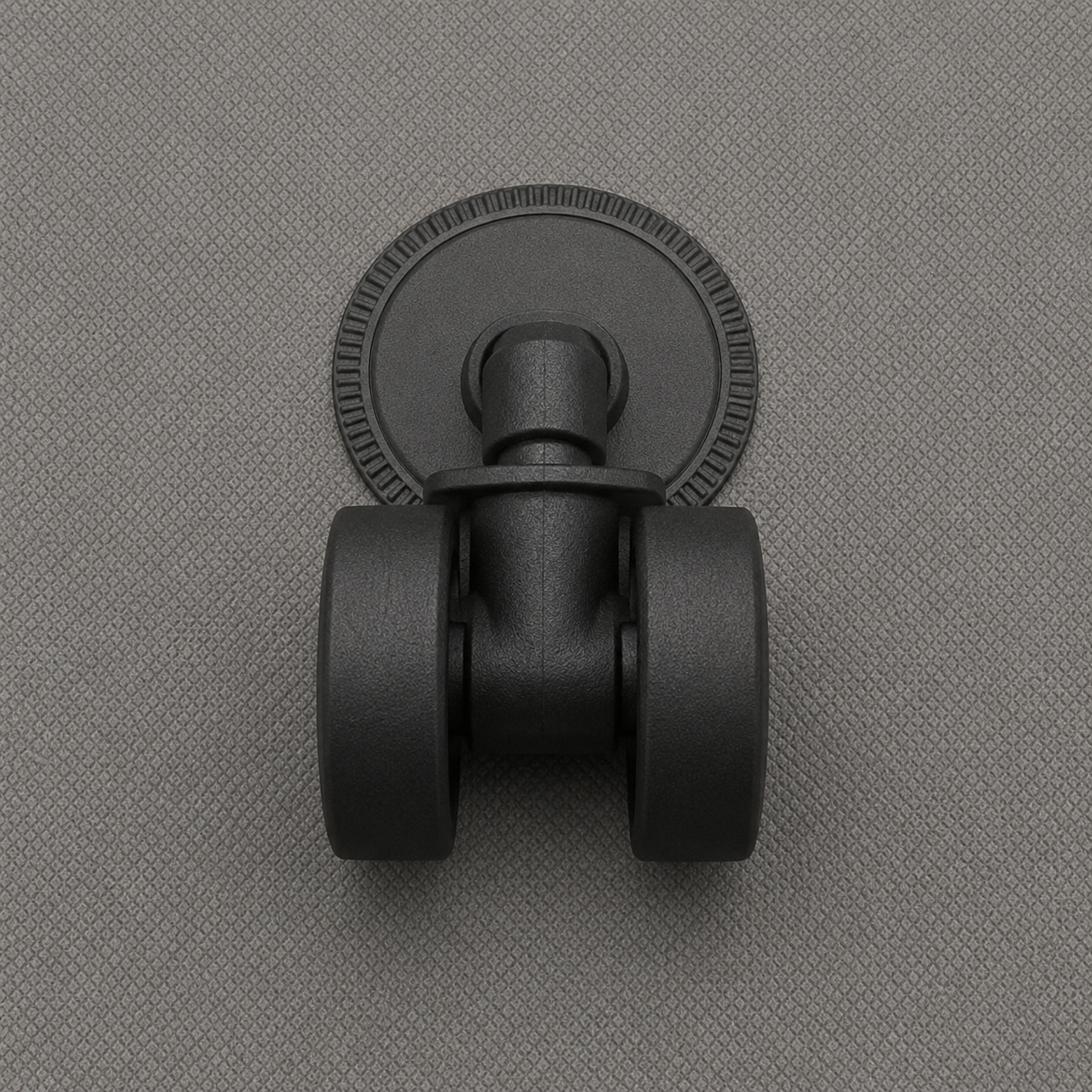 Close-up of one black swivel castor seated in its round socket plate on the gray fabric base of the box.