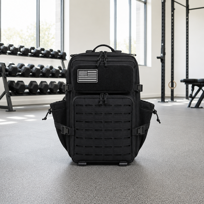 Black laser cut MOLLE tactical backpack standing on a gym floor in daylight
