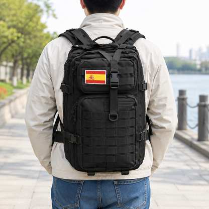Black webbing MOLLE tactical backpack worn on the back on a riverside path, seen from behind