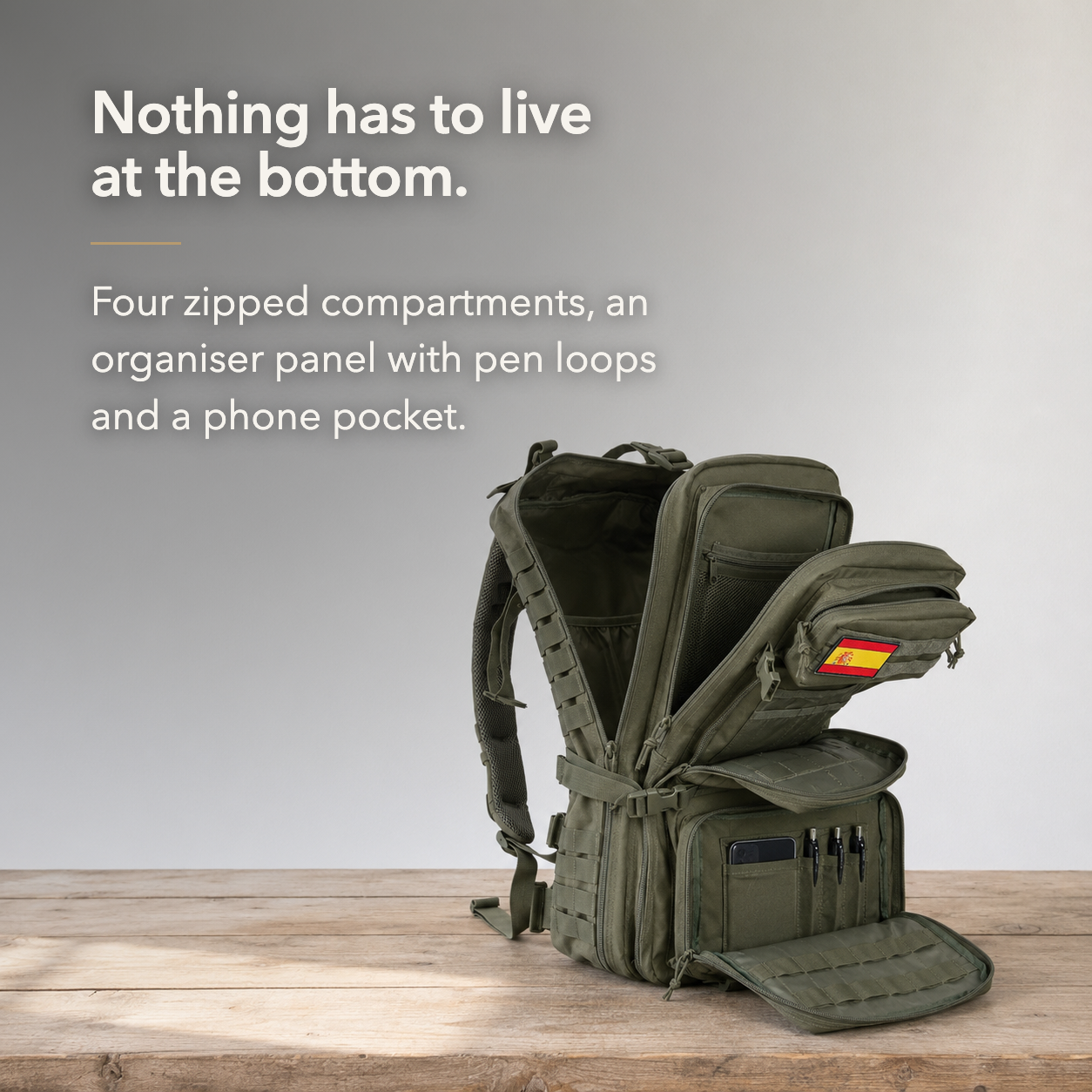 Four zipped compartments open on a workbench, with an organiser panel of pen loops and a phone pocket