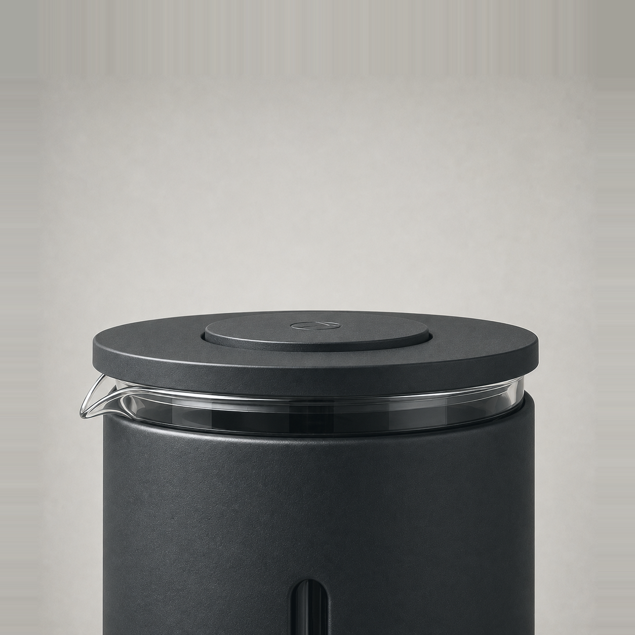 Close-up of the French press lid, its raised press knob and the clear glass pour lip.